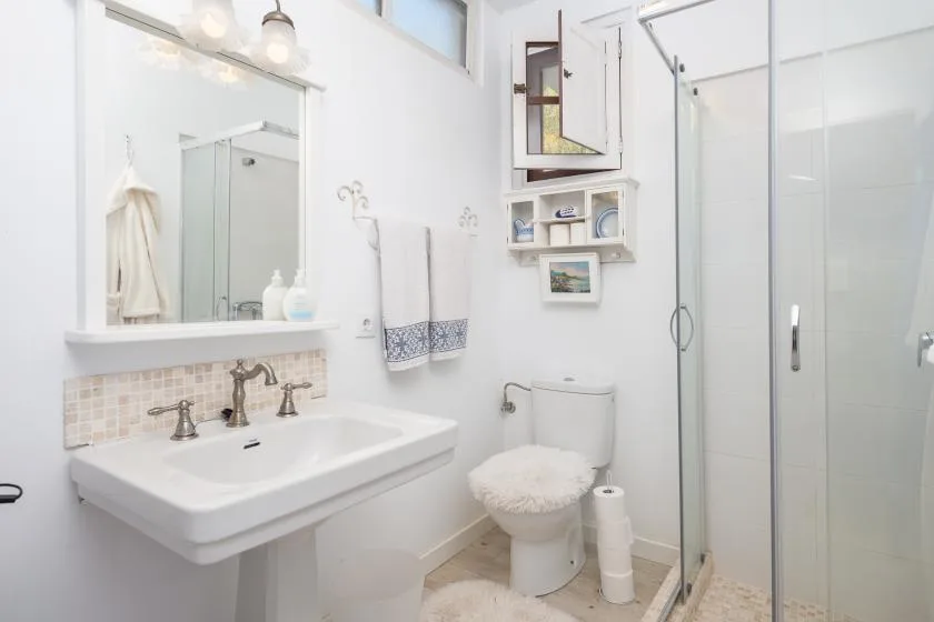 Un baño luminoso con lavabo, inodoro y ducha de vidrio.