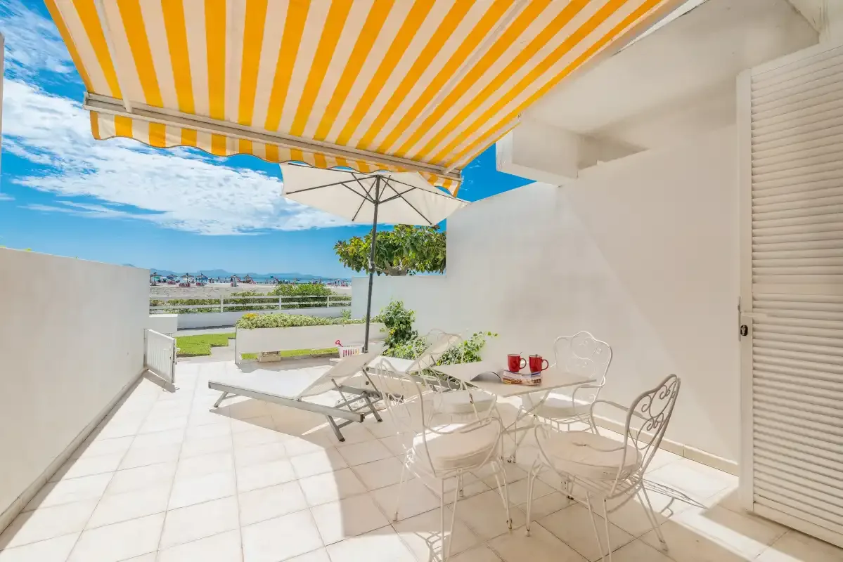 Un patio soleado con toldo a rayas, asientos al aire libre y vistas al paisaje.