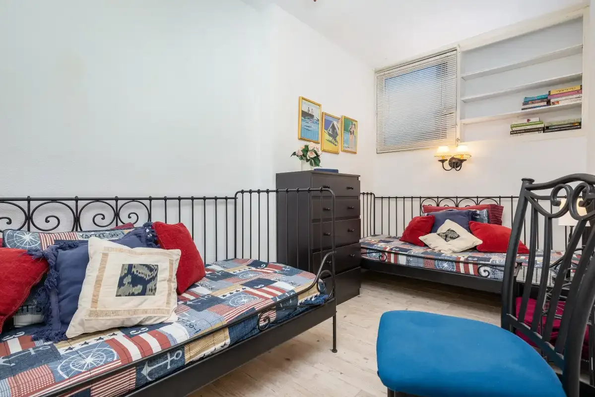 Un dormitorio con ropa de cama estampada y una silla azul.