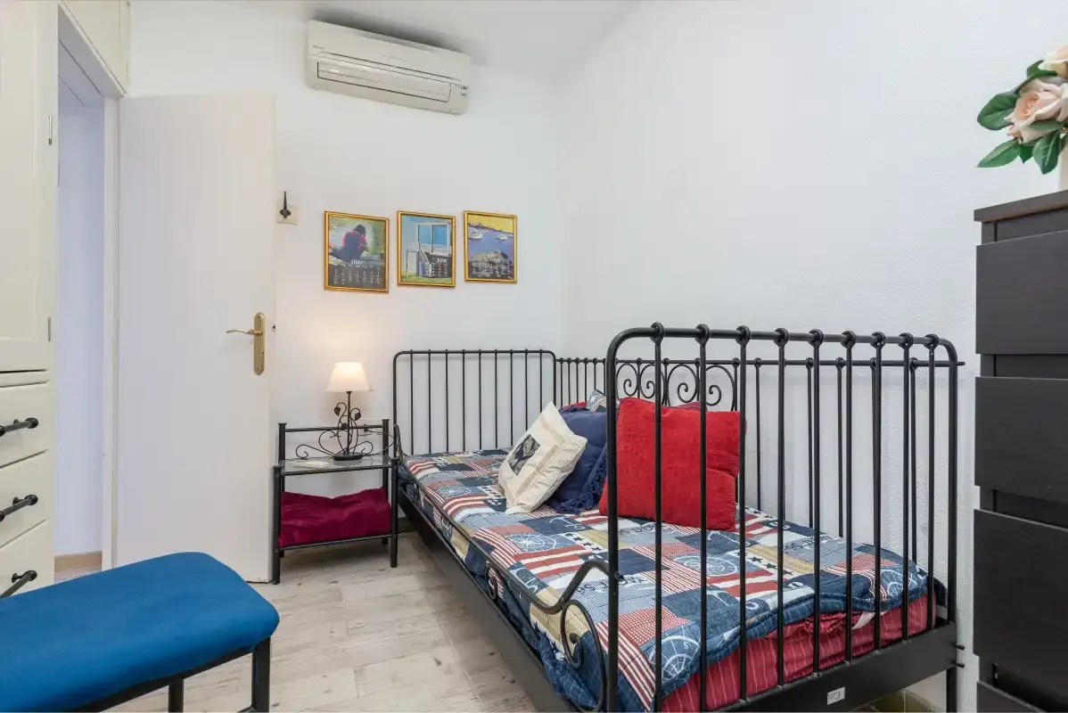 Un dormitorio con una cama de metal negro y ropa de cama estampada de colores.