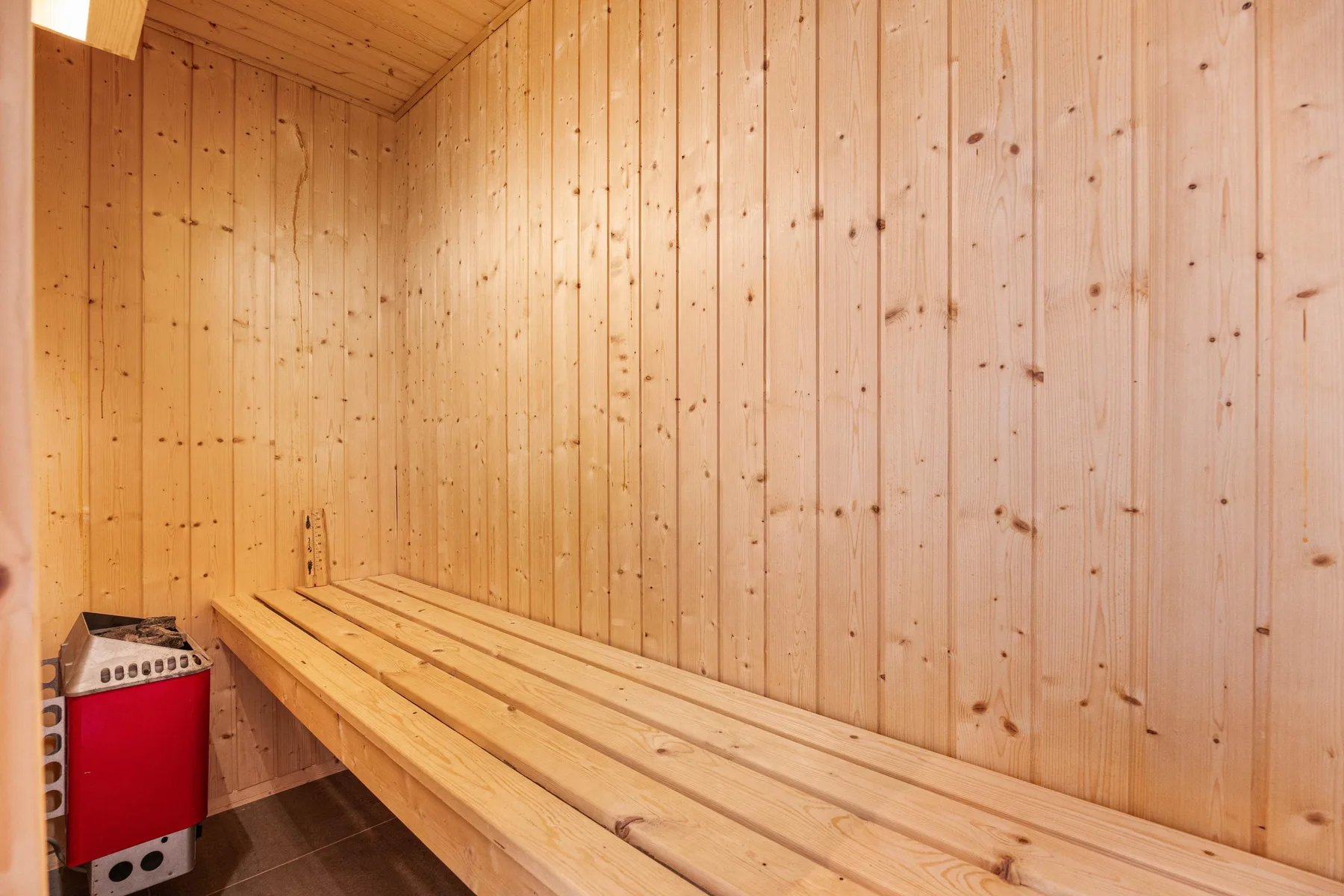 Una sauna de madera con asientos escalonados junto a la pared.