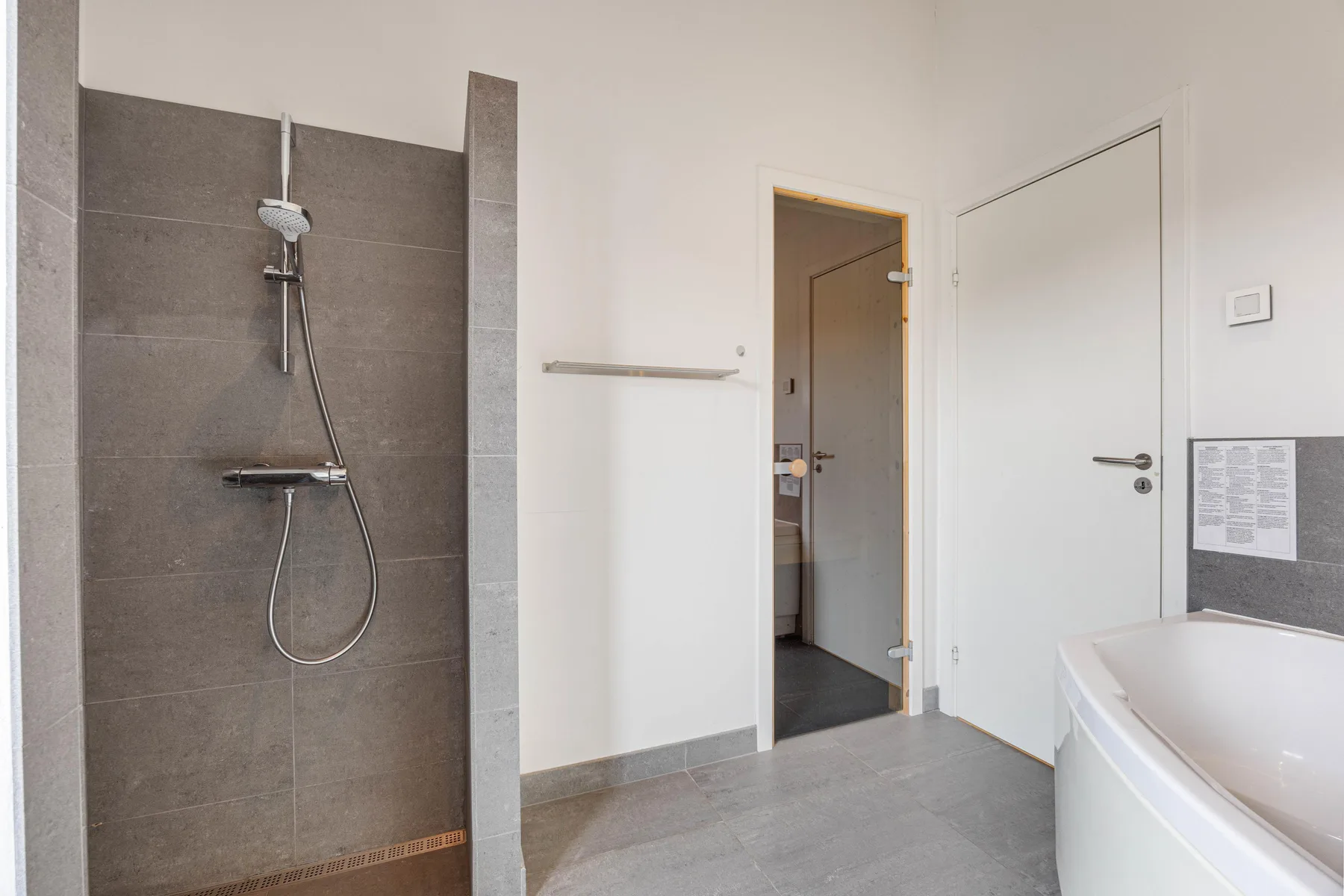 Un baño con ducha, bañera y una puerta.