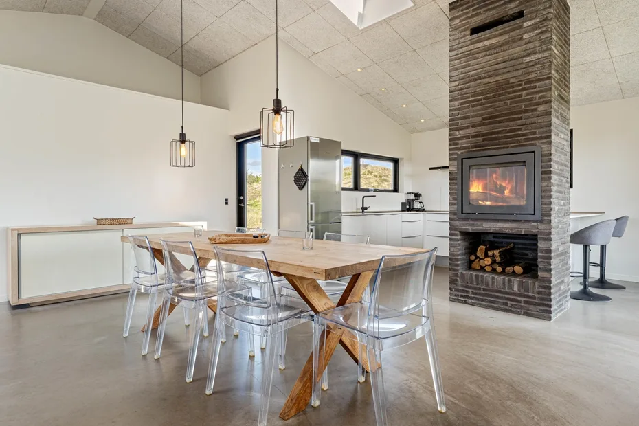 Una cocina abierta con comedor, mesa de madera y chimenea.