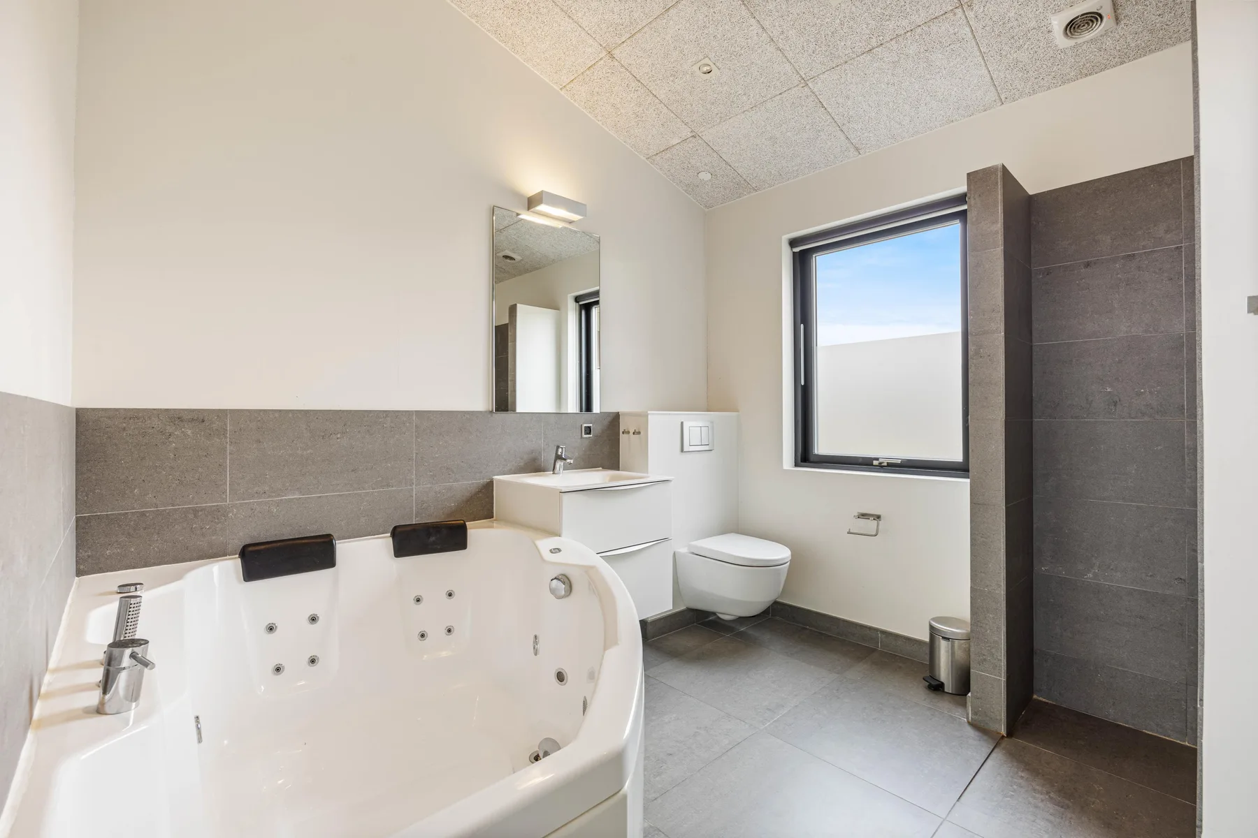 Un baño con una bañera grande, ducha y ventana.