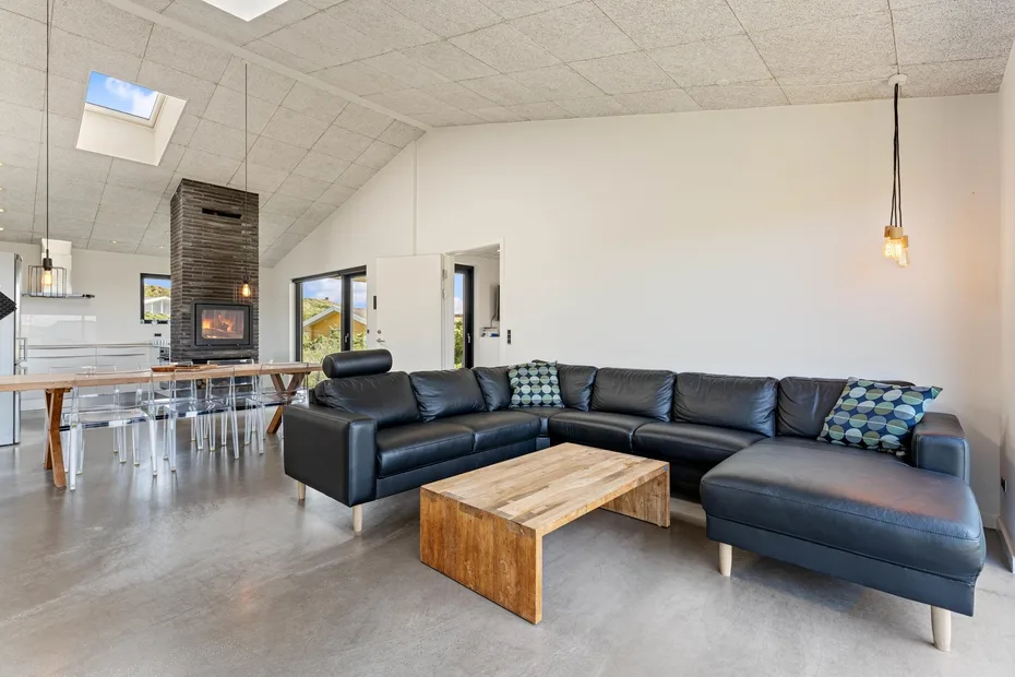 Una amplia sala de estar con asientos oscuros y una mesa de centro de madera.