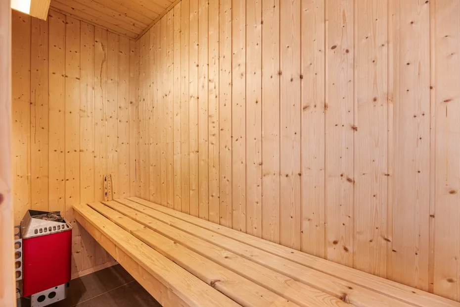 Una sauna revestida de madera con bancos largos y un calentador.