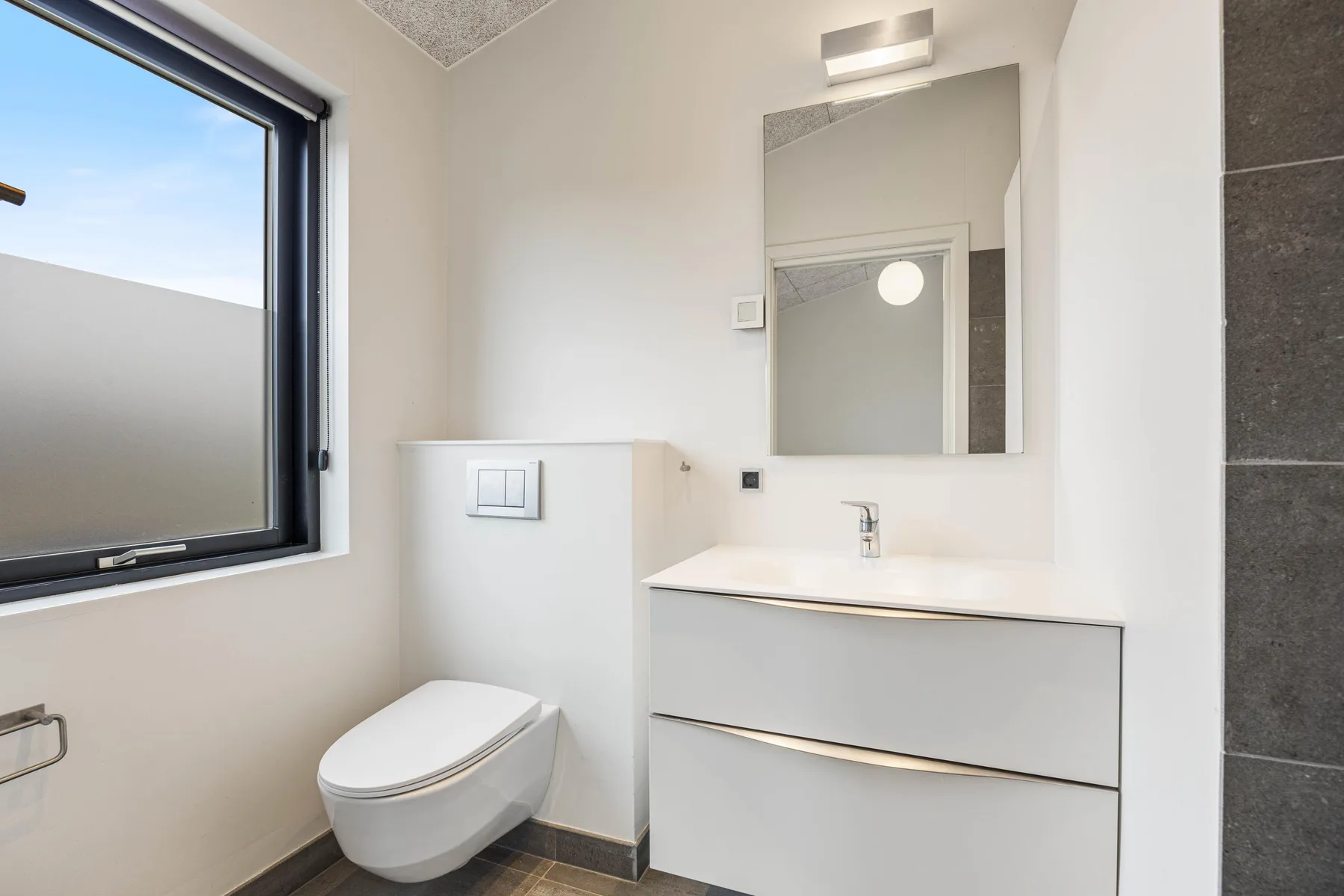 Un baño luminoso con inodoro, lavabo y una ventana grande.