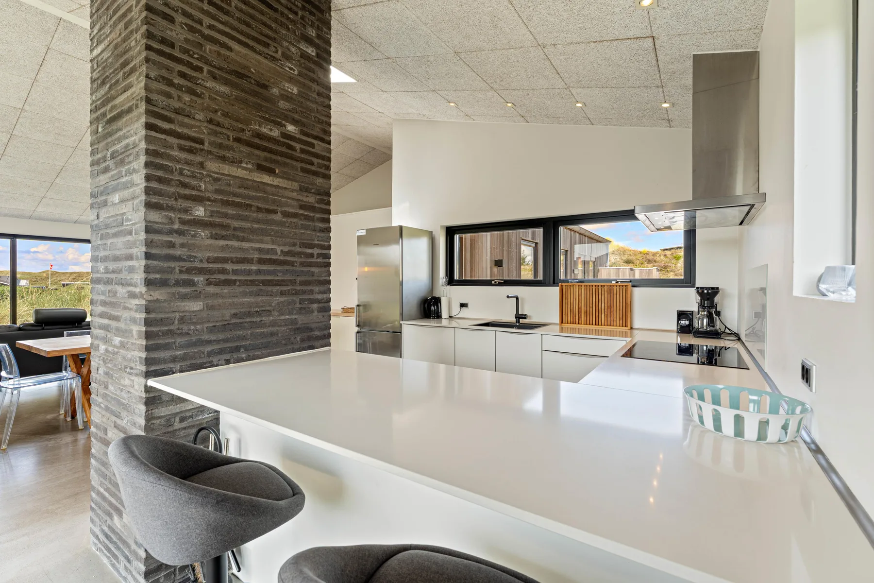 Una cocina luminosa con una gran isla blanca y electrodomésticos integrados.