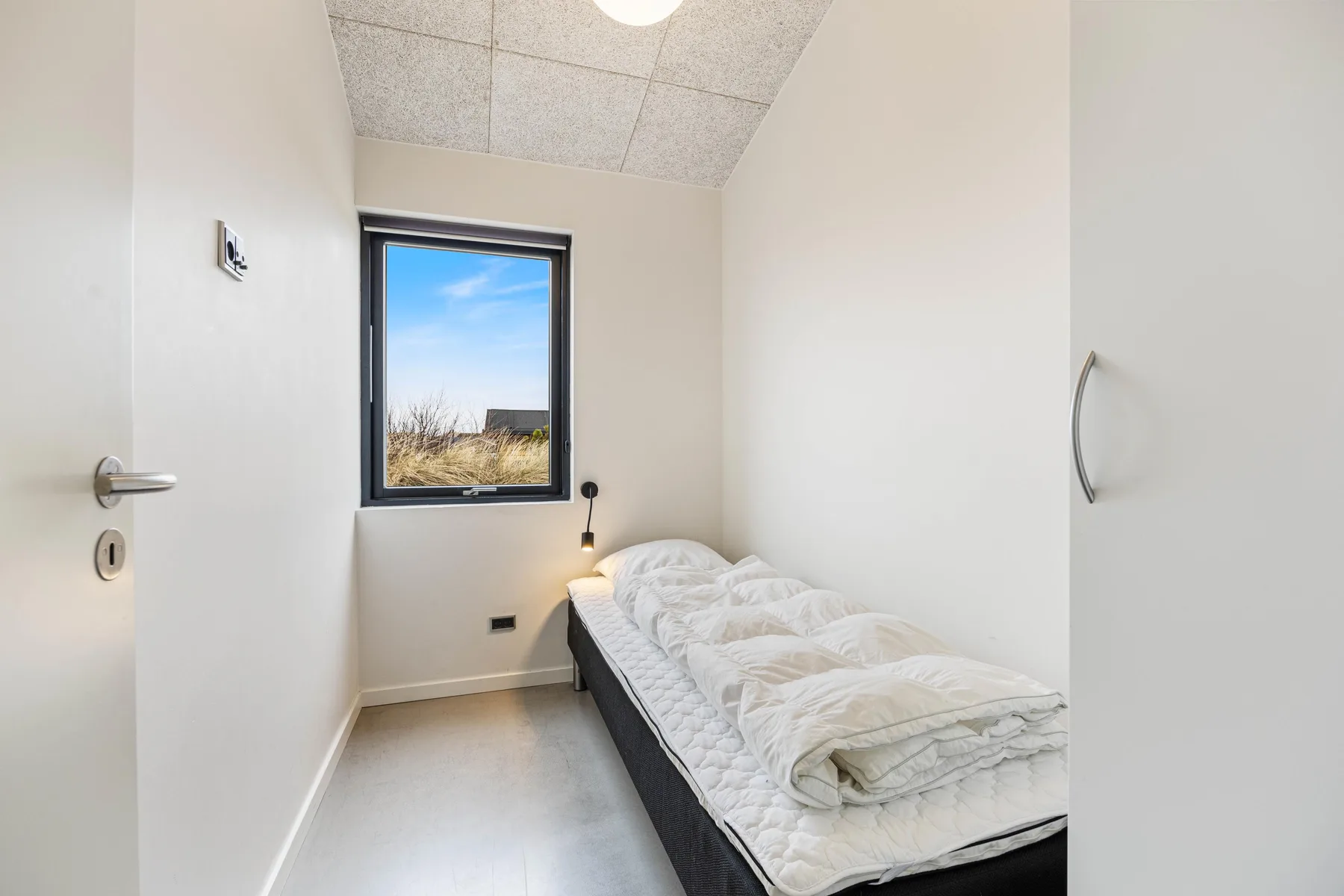 Un dormitorio pequeño con una cama individual junto a una ventana.