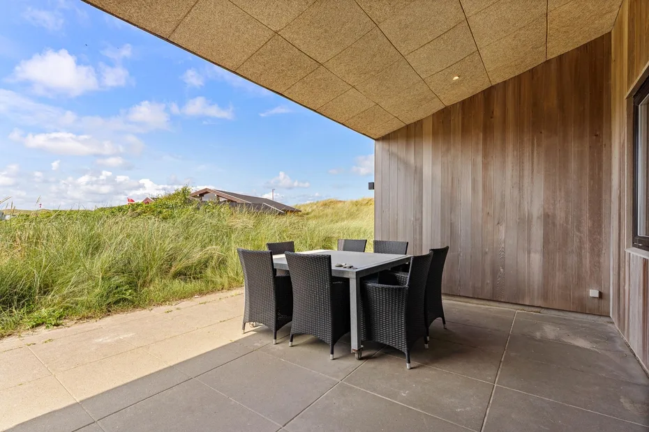 Un patio cubierto con asientos al aire libre da a dunas cubiertas de hierba.