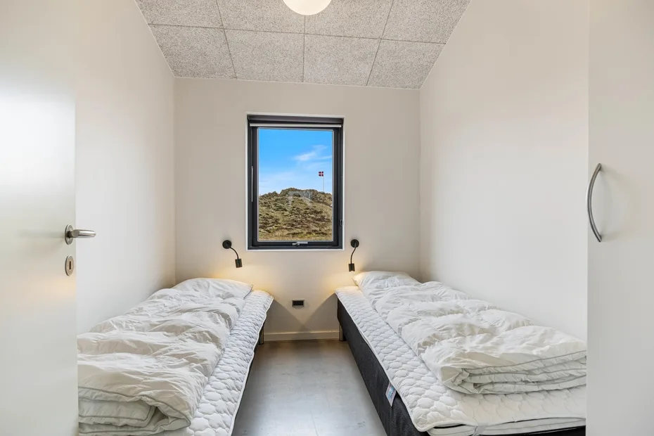 Un dormitorio con dos camas individuales frente a una ventana con vistas a un paisaje de hierba.