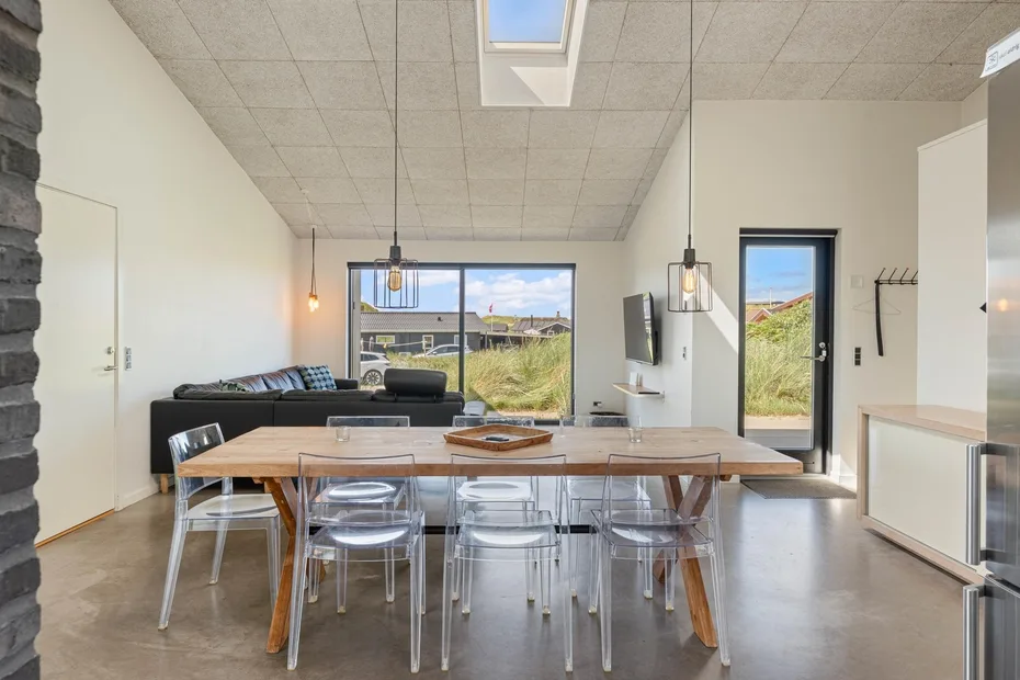 Un comedor con una mesa larga y sillas junto a una zona de estar.