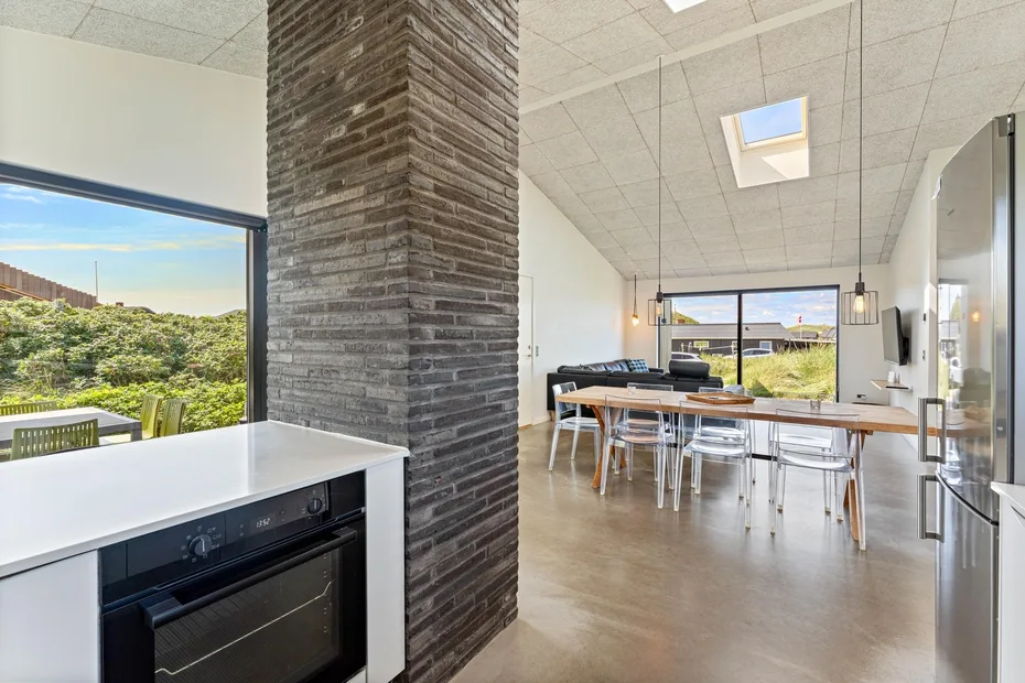 Una luminosa cocina abierta con comedor, grandes ventanas y una mesa larga.