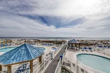Una zona de piscina al aire libre con un pabellón cubierto junto a la playa.