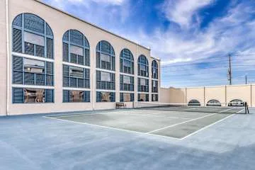 Una cancha pavimentada al aire libre está junto a un edificio con ventanas altas en arco.