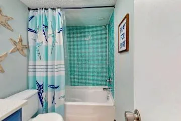 Un baño con bañera, cortina de ducha y pared de azulejos turquesa.