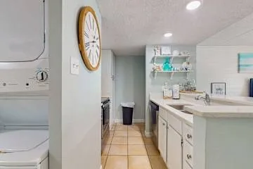 Un cuarto de lavandería con lavadora y secadora junto a una encimera larga.