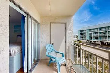 Un balcón con una silla azul y vistas a un edificio cercano.