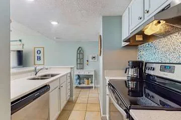 Una cocina compacta con gabinetes blancos y una cafetera sobre la encimera.