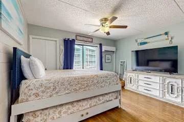 Un dormitorio con cama, ventana y televisor.