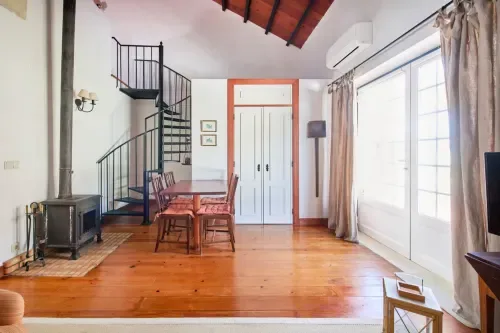 Loft interior with a spiral staircase, wooden floor and dining table.