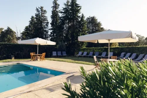 Piscina con tumbonas azules y sombrillas.