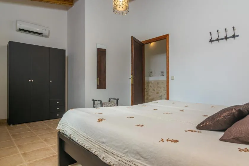 A bedroom with a bed, dark wardrobe, and an open doorway to a tiled bathroom.