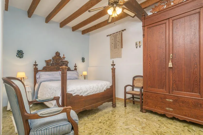 A bedroom with a wooden bed, matching wardrobe, and exposed ceiling beams.