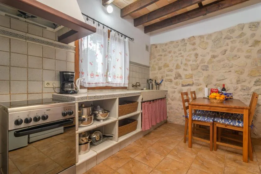 A rustic kitchen with a long counter, stove, and small dining table.
