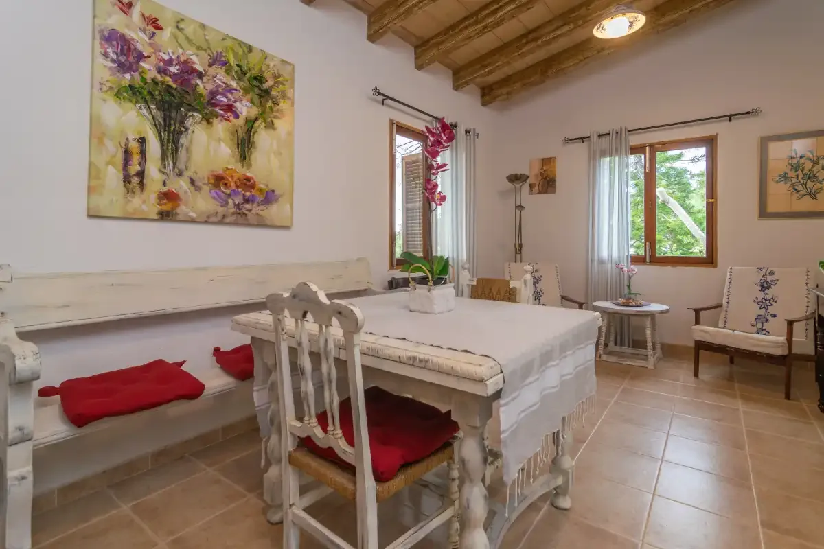A dining area with a long table, cushioned bench, and floral wall art.