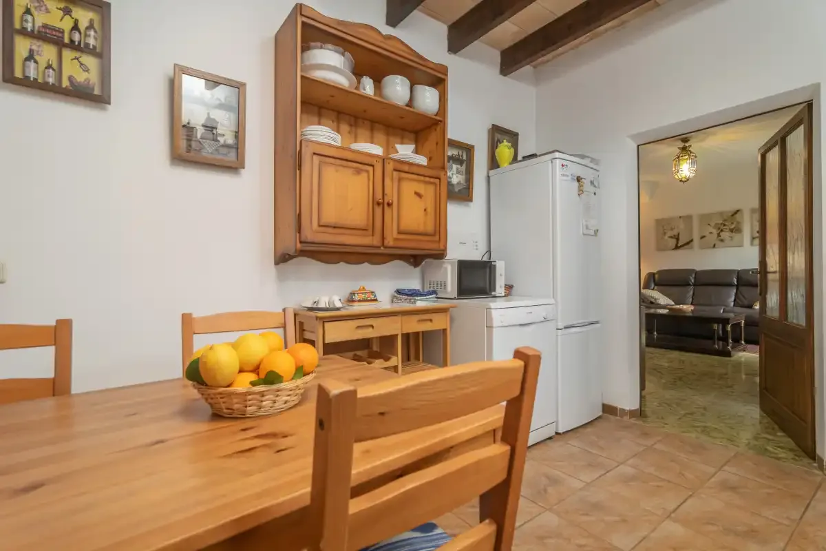 A kitchen and dining area with wooden furniture and an open doorway to a sitting room.