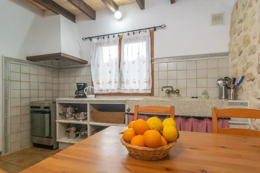 A rustic kitchen with a bowl of oranges on the wooden table.