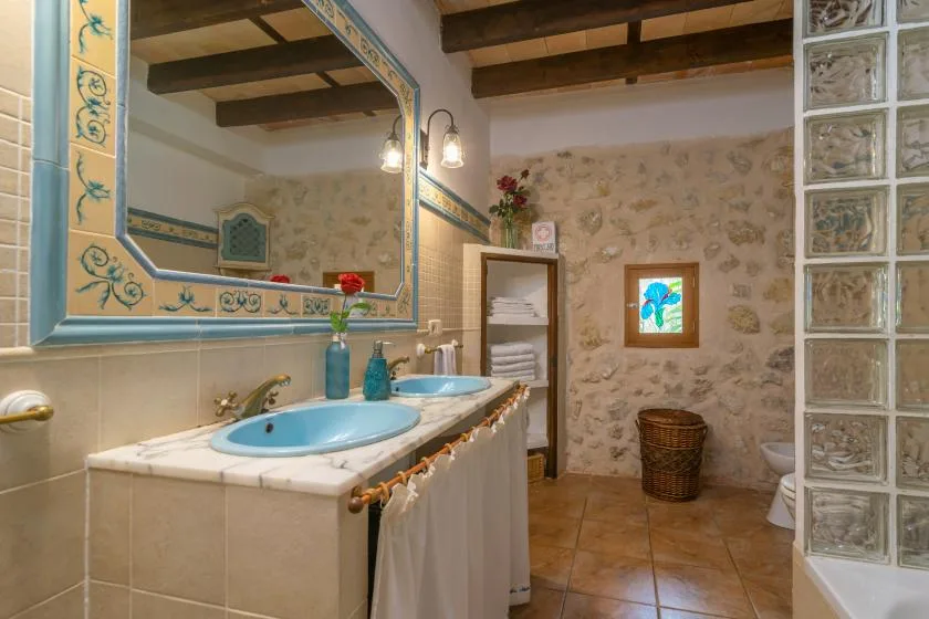 A rustic bathroom with a double sink vanity and decorative wall mirror.