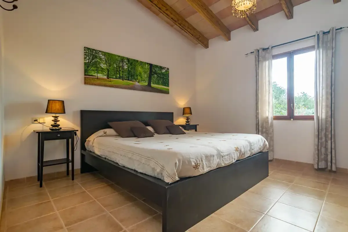 A bedroom with a large bed, bedside tables, and a window.