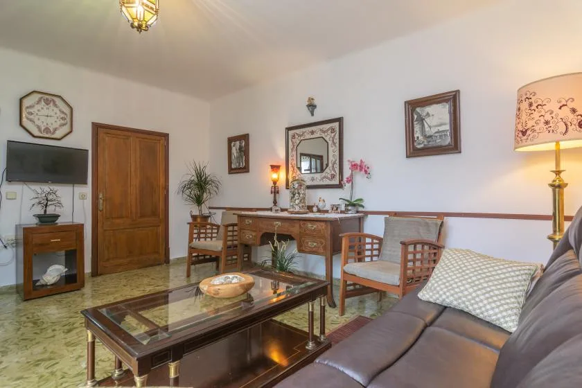 A living room with a sofa, glass coffee table, and wooden furnishings.