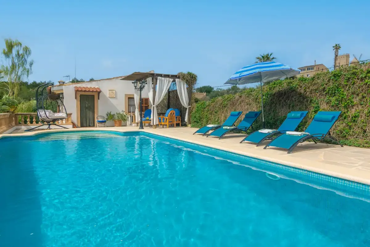 An outdoor swimming pool beside a small building and lounge seating.