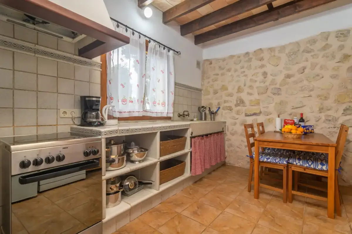 A rustic kitchen with a cooking area and a wooden dining table.