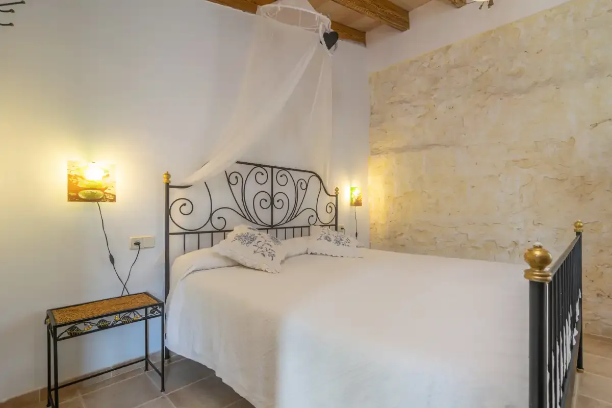 A bedroom with a metal bed and a light stone wall.