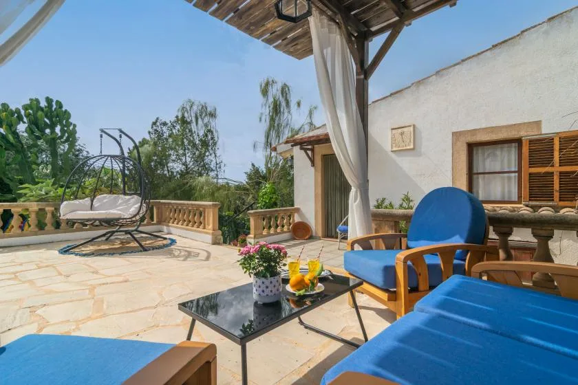A sunny terrace with blue seating, a low table, and a hanging chair.