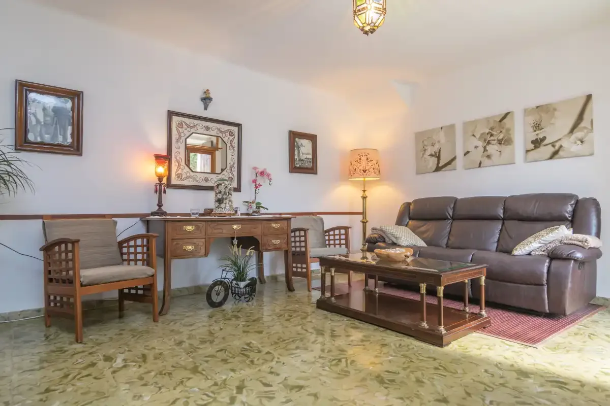 A living room with a sofa, coffee table, and writing desk.