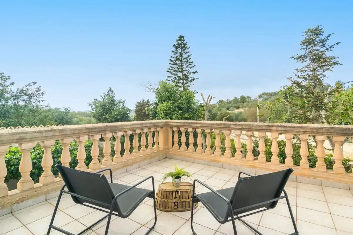 A tiled outdoor terrace with seating overlooks trees and open sky.