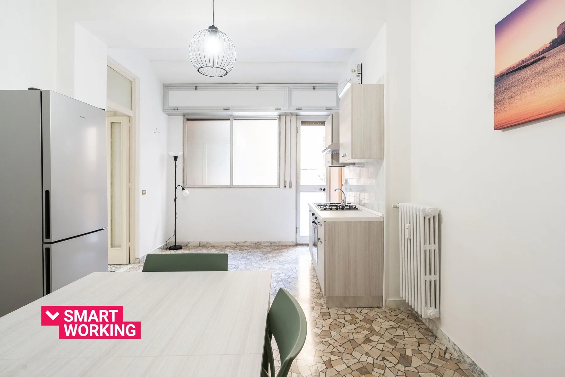 A bright kitchen and dining area with a refrigerator, table, and large window.