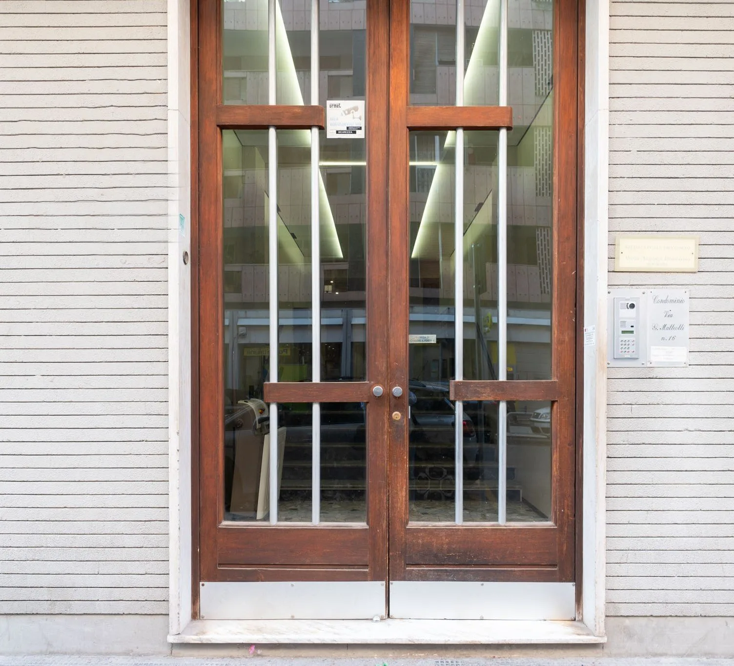 A glass entrance with wooden-framed doors set into a light-colored exterior wall.