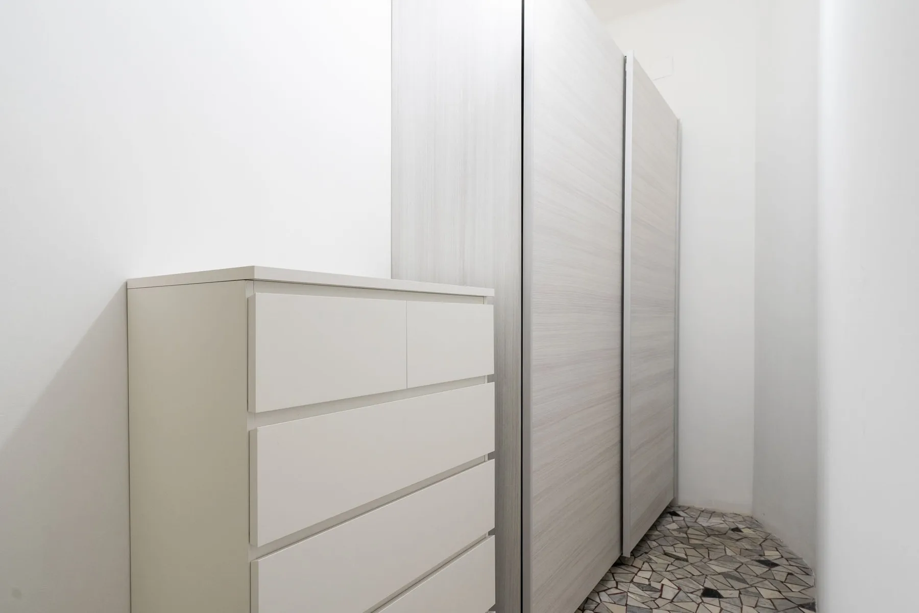 A bedroom storage area with a dresser beside tall wardrobes.