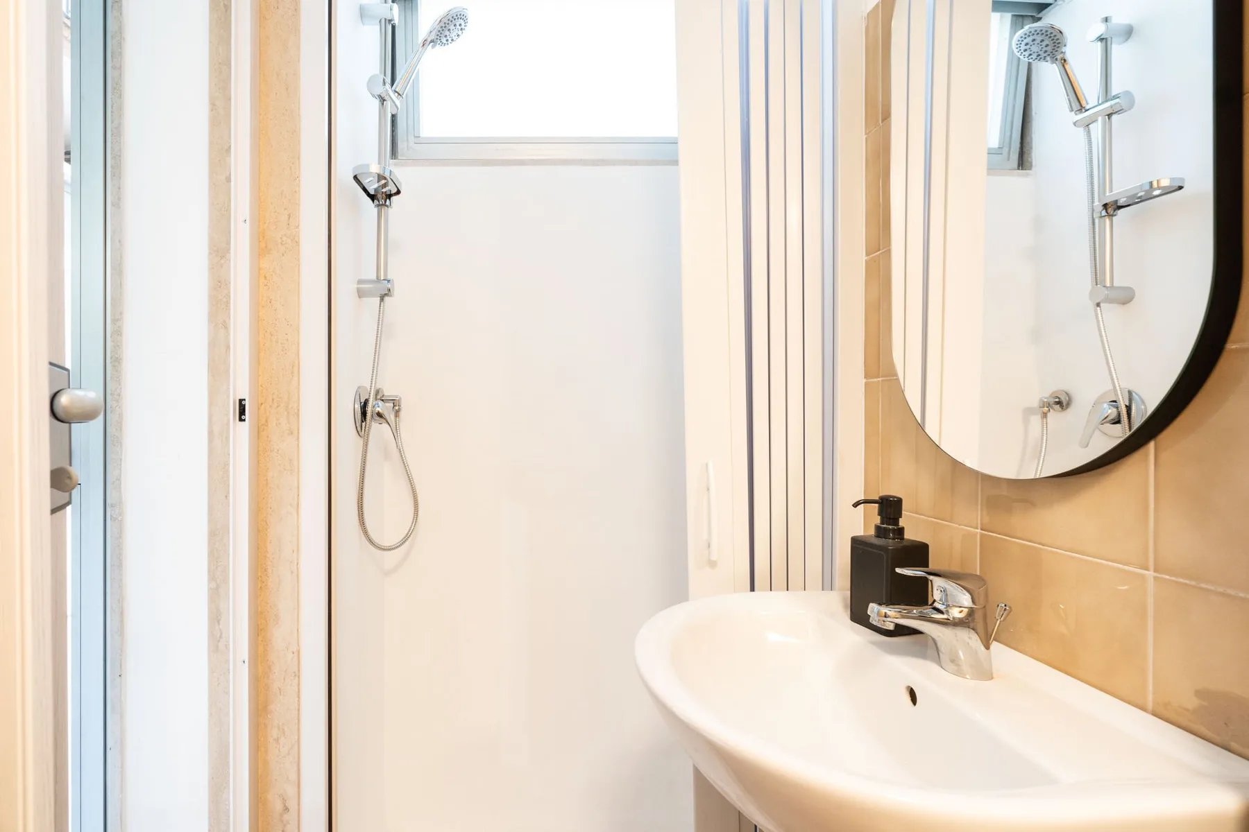 A bright bathroom with a sink, mirror, and shower.