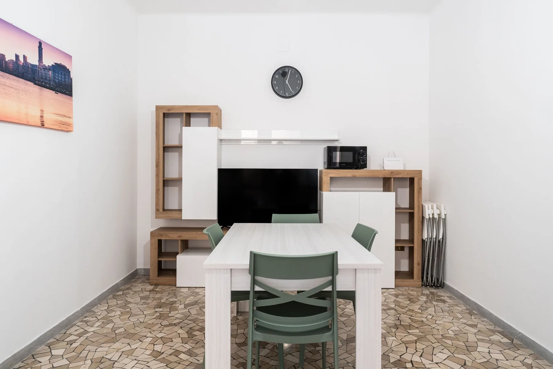 Un comedor con una mesa y asientos verdes, con estanterías junto a la pared del fondo.