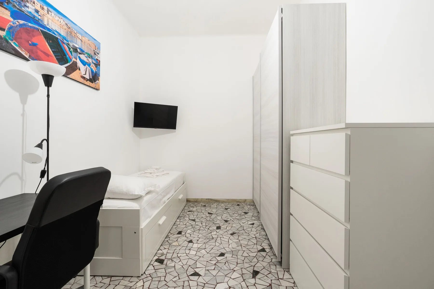 A compact bedroom with a single bed, desk, and tall storage cabinets.