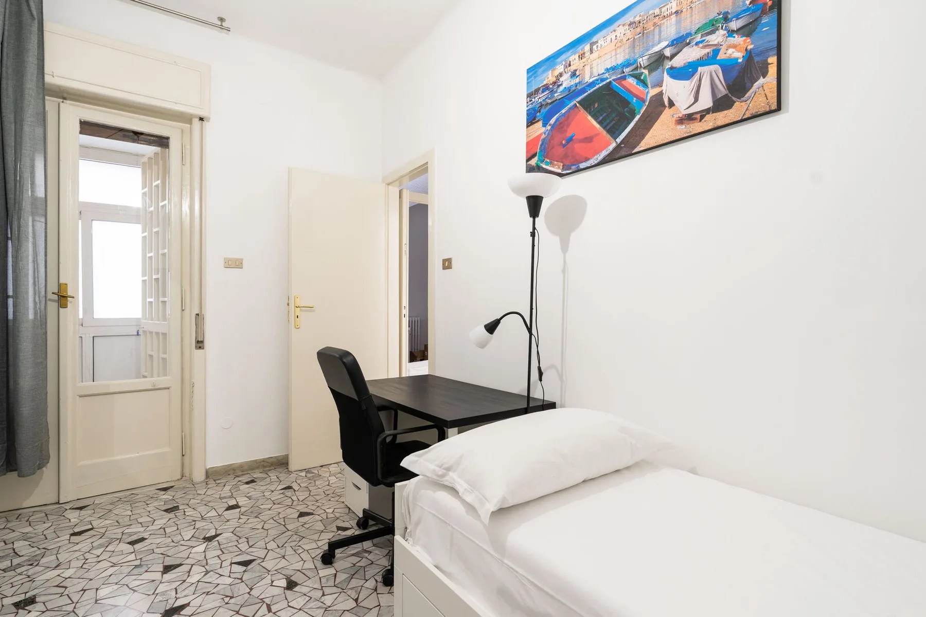 A bright bedroom with a single bed, desk, and chair.