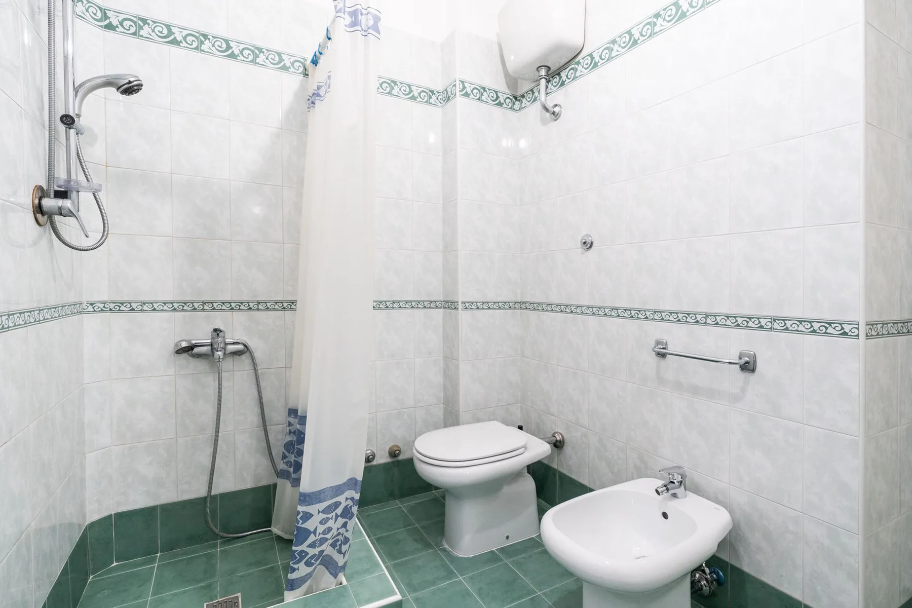 A tiled bathroom with a shower, toilet, and bidet.