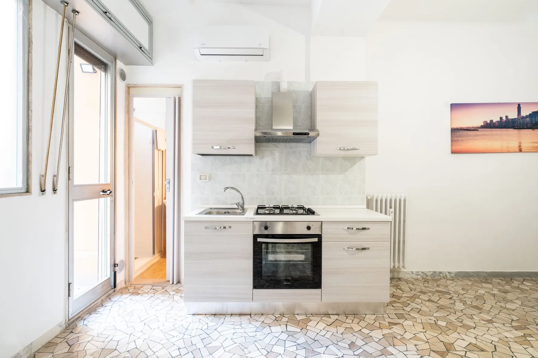 A bright kitchen with light cabinetry, a cooktop, and an oven.